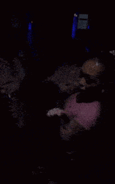 a woman in a pink shirt and shorts is dancing in a crowd of people .