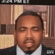 a man in a suit and tie is making a funny face with his eyes closed and his tongue out .