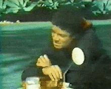 a person is sitting at a table with a white circle on their arm