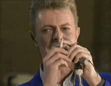 a man in a blue jacket is singing into a microphone and smoking a cigarette