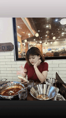 a woman sits at a table in front of a sign that says ' spicy box '