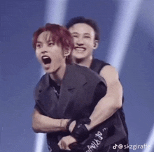 a couple of men are hugging each other on a stage and one of them is making a funny face .