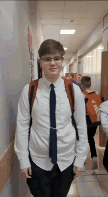 a young man wearing a white shirt and tie is walking down a hallway