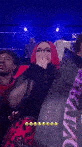 a woman with red hair is covering her face with her hands while sitting in a crowd of people