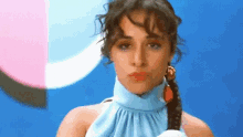 a woman in a blue dress with a braid in her hair is blowing a kiss .