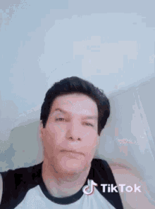 a man wearing a black and white tank top has a tiktok sticker on his chest