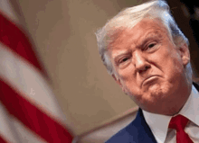 donald trump is making a funny face in front of the american flag