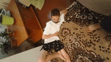 a boy laying on a rug with a white shirt and black shorts