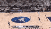 a basketball game is being played on a court with a bird logo on the floor .