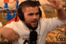 a man wearing headphones and a white shirt is dancing in front of a microphone in a room .