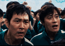 a group of men are standing in a room and one of them is wearing a green shirt that says ' squid game '