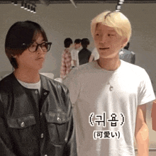 a man wearing glasses and a white t-shirt stands next to another man wearing a black jacket