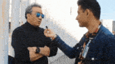 a man wearing sunglasses is talking to another man