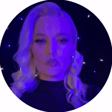 a woman blowing a kiss in front of a purple light