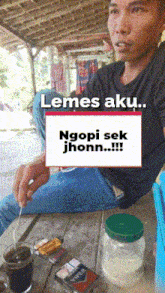a man sitting at a table with a sign that says " lemes aku "