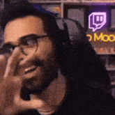 a man wearing glasses and headphones is sitting in front of a neon sign that says moo
