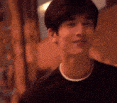 a close up of a young man 's face wearing a black shirt and smiling .