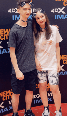 a boy and a girl are posing for a picture in front of a 4dx sign