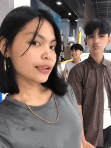 a girl with a gold chain around her neck stands next to two boys