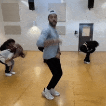 a group of people are dancing in a room with a door in the background