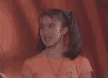 a young girl wearing a microphone and a necklace with the word nintendo on the front
