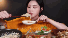 a woman is eating a salad with a spoon and chopsticks .
