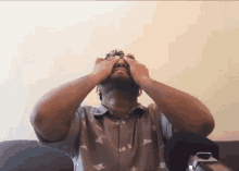 a man covering his eyes with his hands while sitting on a chair