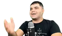 a man is talking into a microphone while wearing a black shirt .