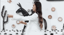 a woman in a white jacket is standing in front of a black and white drawing of a man on a donkey
