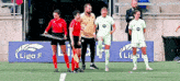 a group of people standing on a soccer field with a sign that says liga f on it