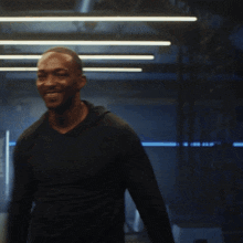 a man wearing a black shirt is smiling in a dark room