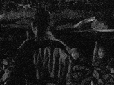 a group of men are standing around a fire with one man pointing