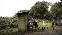 a group of people are trying to get out of a small wooden building