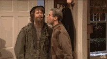 two men are standing next to each other in front of a door .