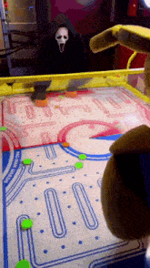 a person in a scream mask is playing a pinball game