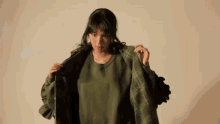a woman is wearing a green sweater and a green jacket .