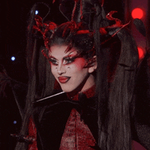 a woman in a red and black costume has a x on her face