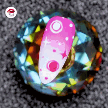 a nail with pink and white circles and dots on it