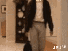 a man is walking down a hallway with a suitcase and a backpack .