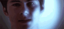 a close up of a young man 's face with a light shining on it .