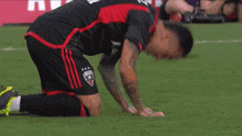 a soccer player is kneeling down on the field with a sign in the background that says ' a '