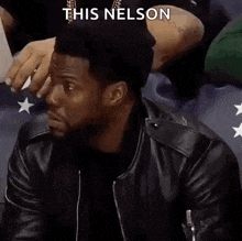 a man in a black leather jacket is sitting in a stadium and says alright then