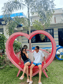 a man and woman sit on a heart shaped chair
