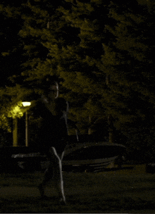a woman in a black dress is walking in the dark