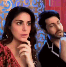 a man and a woman are sitting next to each other and the woman is looking at the man 's face .
