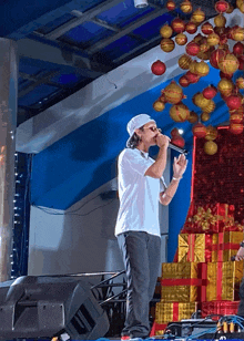 a man singing into a microphone in front of a bunch of christmas decorations