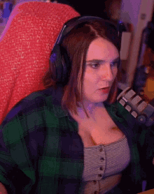 a woman wearing headphones and a plaid shirt is sitting in front of a microphone