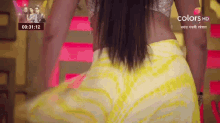 a woman in a yellow skirt is dancing in front of a pink background .