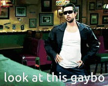 a man wearing sunglasses and a leather jacket stands in a diner with the words look at this gaybo written below him