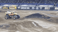 a monster truck is driving on a dirt track in front of a lucas oil advertisement